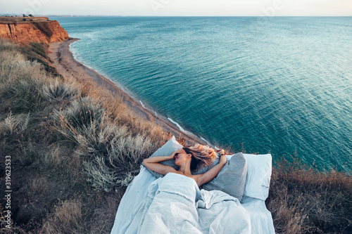 Woman enjoying view on beach landscape while relaxing in bed in sunset on the edge of Earth photo