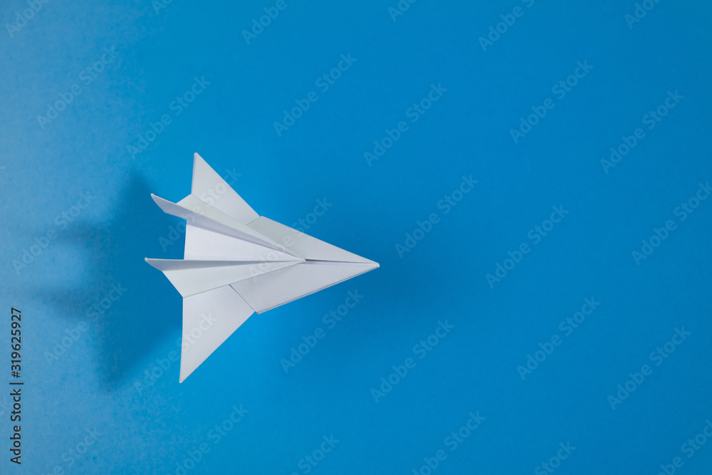 White paper jet flies above blue background. Top view White paper jet flies above blue background. Top view