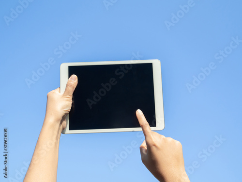 finger touching screen with blue backgroun, isolated on blue sky