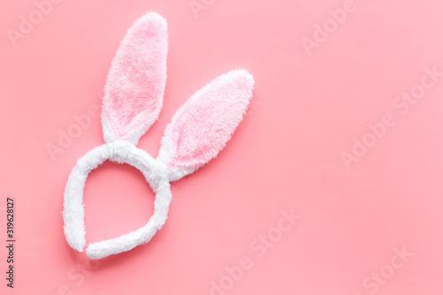 Easter bunny concept. Toy rabbit's ears for head on pink background top-down copy space