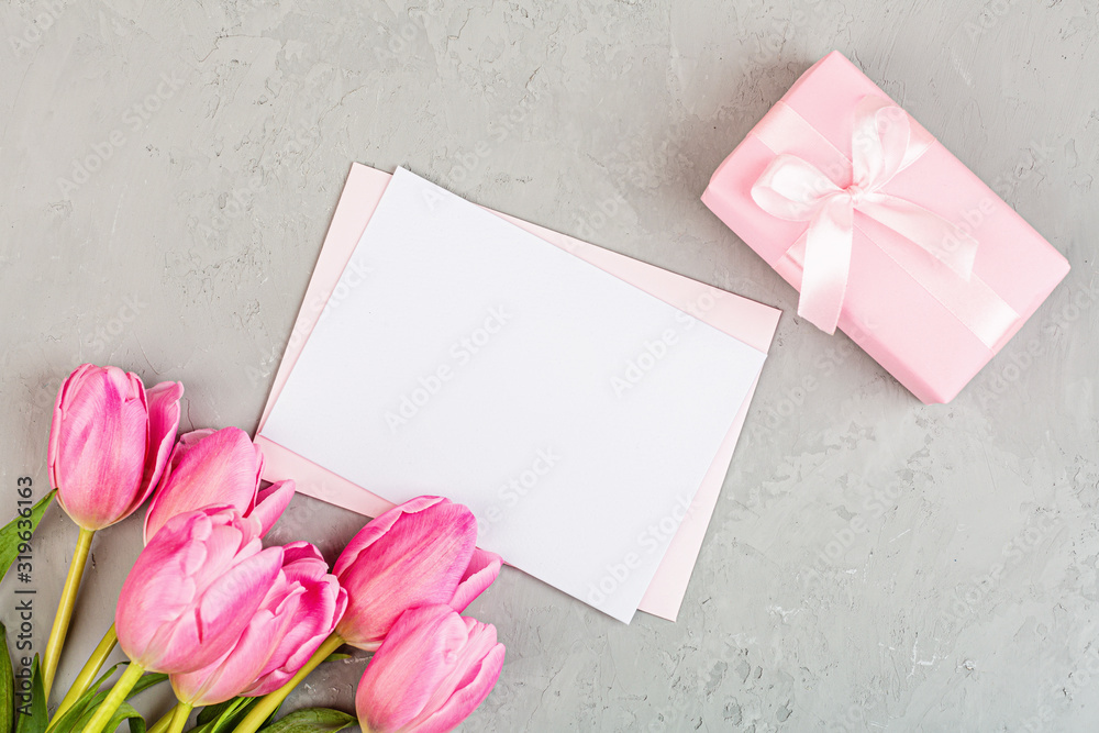 View from above tulips and gift box with copy space on gray concrete background. Womens day, 8 March Valentines day, 14 february. Flat lay style, top view, mockup, template, overhead. Greeting card View from above tulips and gift box with copy space on gray concrete background. Womens day, 8 March Valentines day, 14 february. Flat lay style, top view, mockup, template, overhead. Greeting card