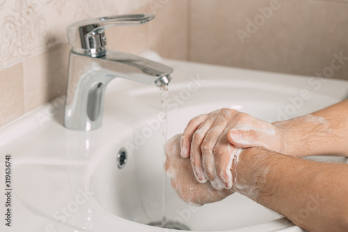 Washing hands under the water tap or faucet without soap. Hygiene concept detail. Beautiful hand and water stream in bathroom.