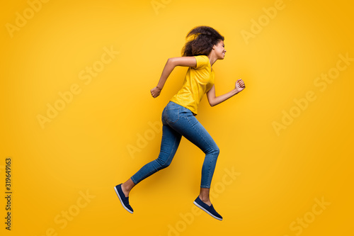 Full length body size profile side view of her she nice attractive lovely cheerful cheery wavy-haired girl running active life isolated on bright vivid shine vibrant yellow color background