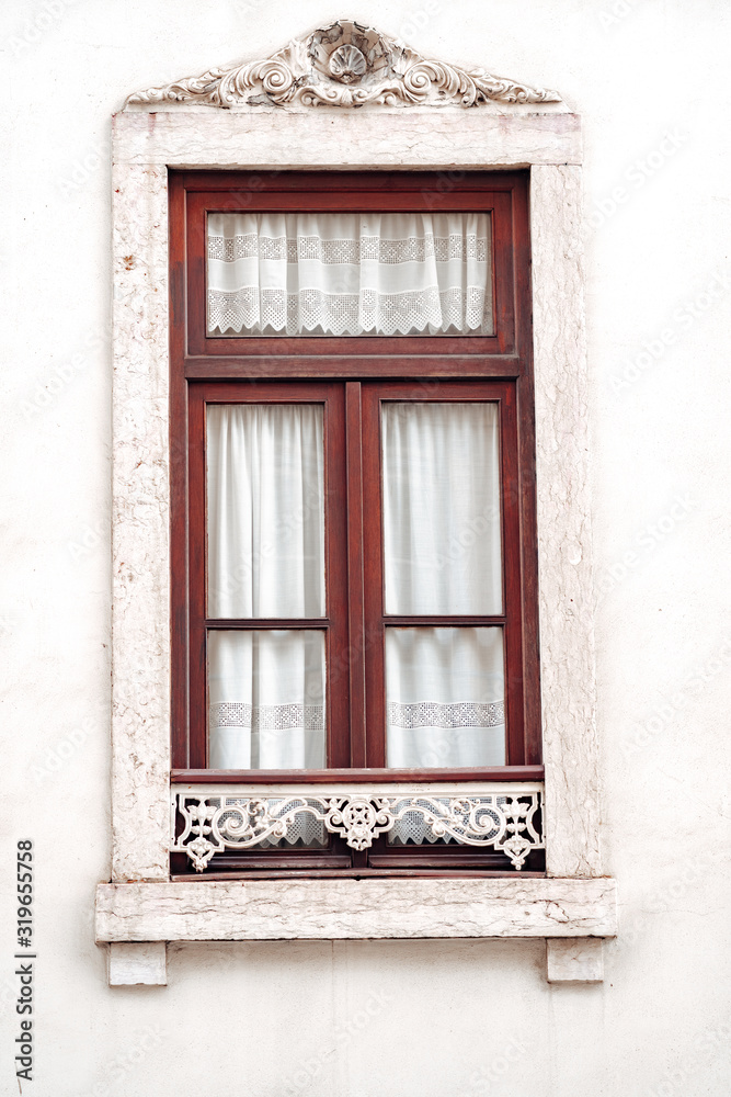 Ornate window with white moulding and lace curtains, typical of the architecture of Lisbon, Portugal