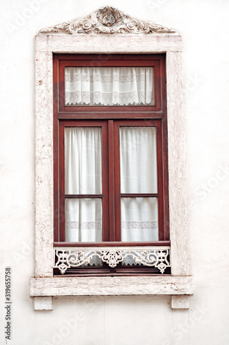 Ornate window with white moulding and lace curtains, typical of the architecture of Lisbon, Portugal