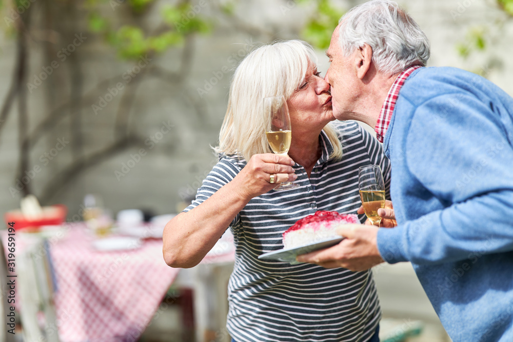 Naklejka premium Paar Senioren küsst sich auf einer Gartenparty