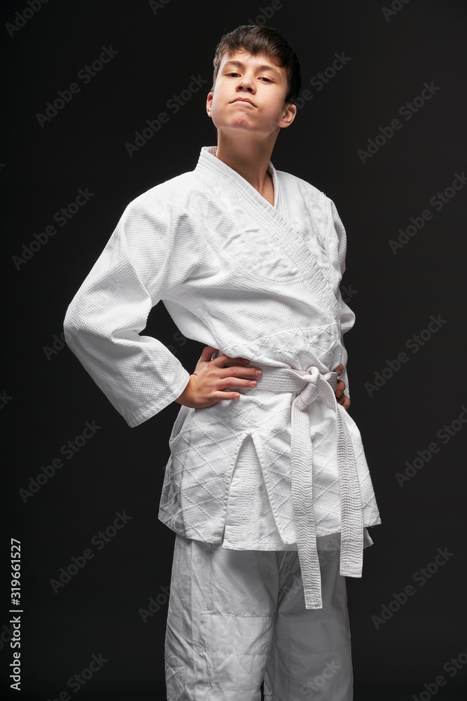 sport concept - a proud teenager dressed in martial arts clothing poses on a dark gray background, studio shoot sport concept - a proud teenager dressed in martial arts clothing poses on a dark gray background, studio shoot