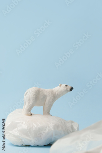 White polar bear on plastic bag on blue background, plastic pollution and climate change concept