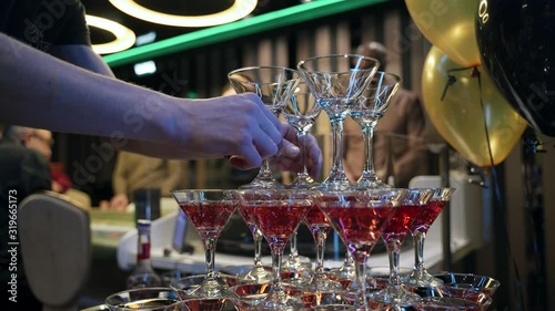 Casino: Red acloholic champagne Pyramid nearby roulette on a balloons background.  Сhampagne bottle. Bartender pours champagne. Close-up photo