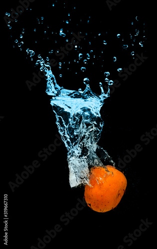 Tangerine falls into the water with splashes