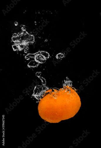 Tangerine falls into the water with splashes