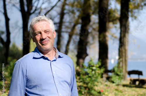 Happy Man with Grey Hair in the Forest.