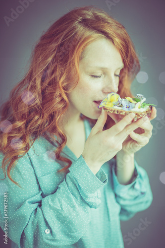 Englisch  Woman with red hair eats healthy bread and edible flowers
