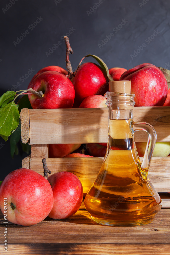 Homemade fruit canning, diet healthy food and drink. Apple cider vinegar, juice, salad dressing from a crop of ripe red garden fruits in a glass jug on a wooden rustic background Homemade fruit canning, diet healthy food and drink. Apple cider vinegar, juice, salad dressing from a crop of ripe red garden fruits in a glass jug on a wooden rustic background