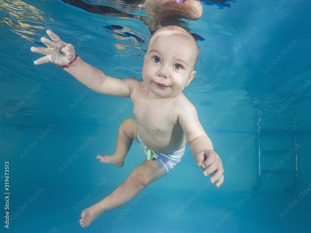 Little boy swims underwater in a swimming pool