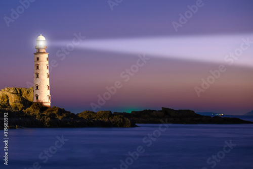 Lighthouse on sea sunset with light beacon at night landscape