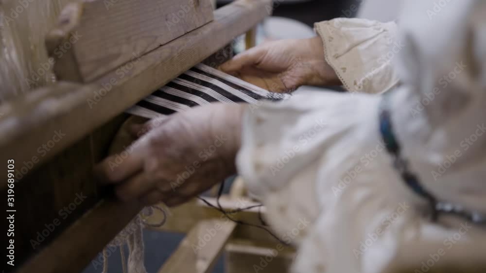 Old woman using a traditional hand weaving loom Old woman using a traditional hand weaving loom