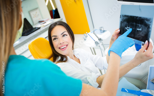 Female doctor shows the patient an x-ray image dental tomography. Planning teeth treatment.