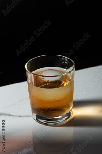 ice cube in glass of whiskey isolated on black