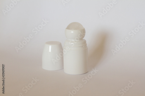 Body antiperspirant deodorant roll-on, open and closed empty white bottle with screw cap. antiperspirant on a pink background with shells. space for text. Busty white tube and the bubble.