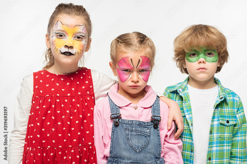 displeased friends with colorful face paintings looking at camera isolated on white displeased friends with colorful face paintings looking at camera isolated on white