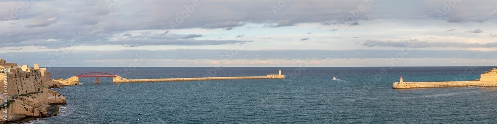 Old lighthouse and breakwater bridge of Fort Ricasoli from Valletta in Malta