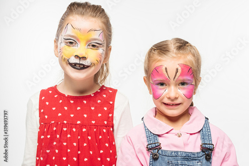 cute friends with cat muzzle and butterfly paintings on faces smiling at camera isolated on white
