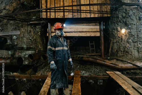 Photography A man wearing a helmet and a respirator stands in the mine.