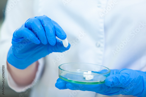 Technician holding Petri dish with pills. Scientists create new drugs and vaccines in a modern scientific laboratory