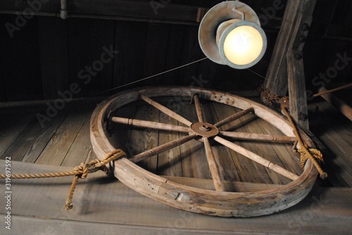 Vintage wooden wagon wheel mounted in a wall.