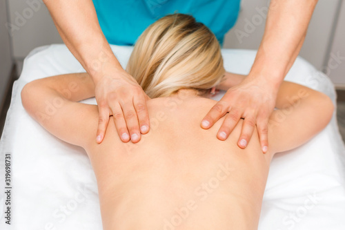 Hands of a massage therapist doing back massage of a woman. Young woman having body sculpting procedure. Chiropractic back adjustment. Osteopathy, alternative medicine, pain relief concept.