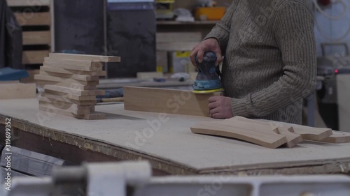 Foto a man without protective equipment polishes a wooden block with an electric grinder
