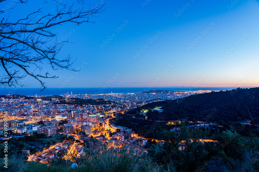 Obraz premium Skyline horizonte en atardecer con color azul y calles iluminadas naranjas desde mirador del mirador del tibidabo