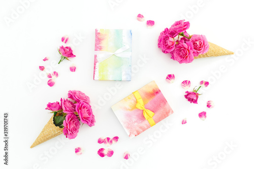 Floral composition with pink roses and gifts on white background. Flat lay, top view. Woman day or Valentines day