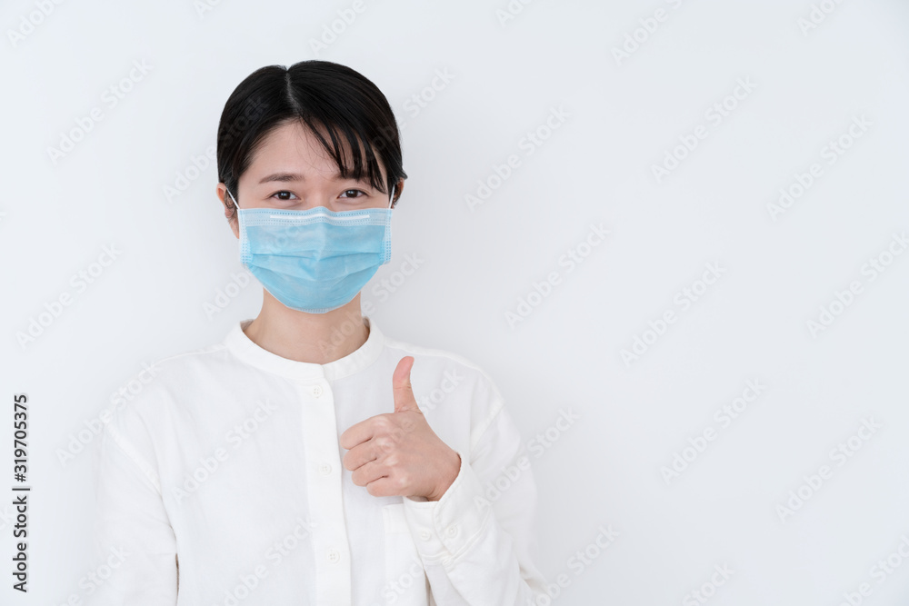 Asian woman wearing a protective mask and giving thumbs up sign Asian woman wearing a protective mask and giving thumbs up sign