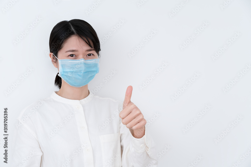 Asian woman wearing a protective mask and giving thumbs up sign Asian woman wearing a protective mask and giving thumbs up sign