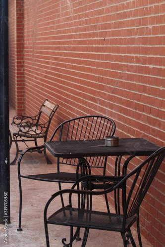 Table and chairs at a patio, with a red brick wall © raksyBH