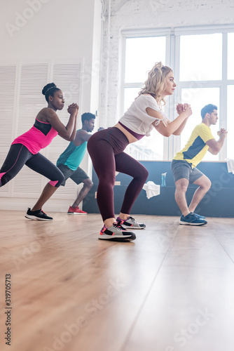 Low angle view of multiethnic zumba dancers stretching while training in dance studio