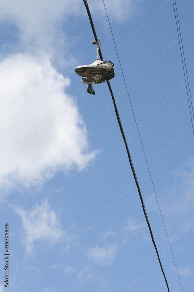 Upward portrait shot of running shoes hanging from electric wires Upward portrait shot of running shoes hanging from electric wires