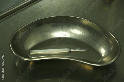 Metal tray, scalpel and medical glove on metal table in medical office photo