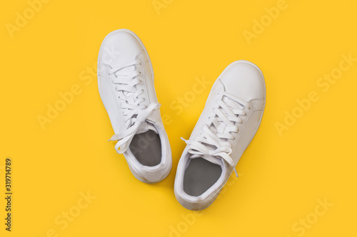 Zapatillas blanca sobre fondo amarillo liso brillante. Vista superior. Copy space photo