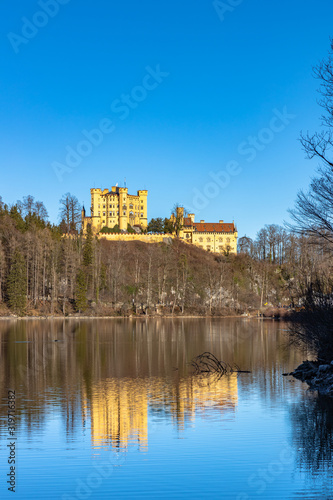 Stunning view of the Alpsee lake in winter on a sunny day with the Hohenschwangau Castle and Bavaria Alps in background, with beautiful reflections in water, Schwangau, Bavaria, Germany