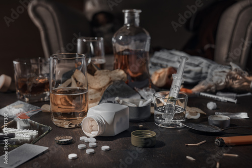 Various drugs  alcohol and cigarettes are on the wooden table. Substances that cause drug and alcohol dependence. Low key.