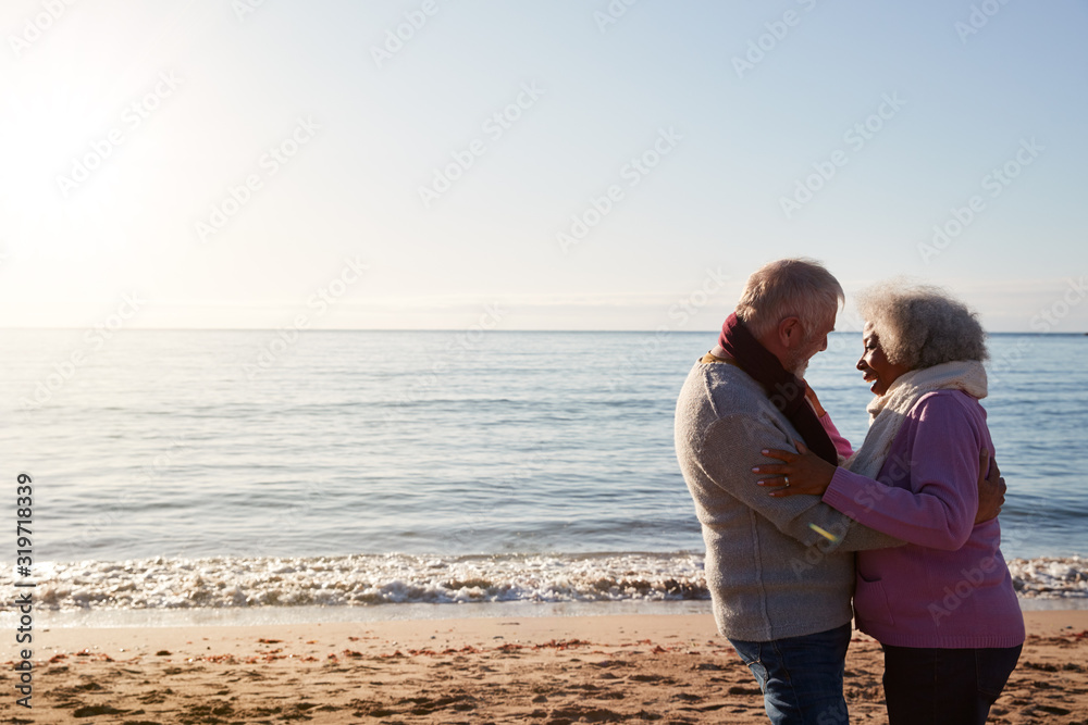Profile View Of Loving Retired Couple Hugging Standing By Sea On Winter Beach Vacation Profile View Of Loving Retired Couple Hugging Standing By Sea On Winter Beach Vacation