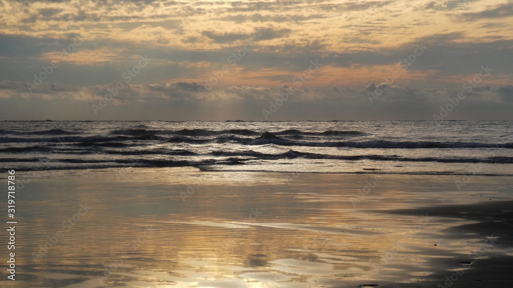 Fototapeta premium sunset over the sea, reflecting on beach