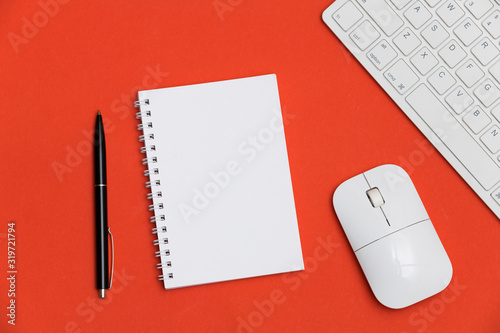 Minimal workplace with blank notepad, keyboard and supplies on colored background. Top view. Flat lay