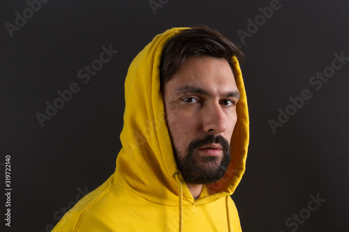 man in a yellow sweatshirt on a dark background