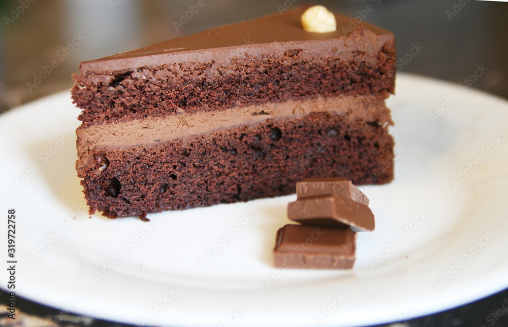 chocolate piece of cake with chocolate pieces on a white plate chocolate piece of cake with chocolate pieces on a white plate