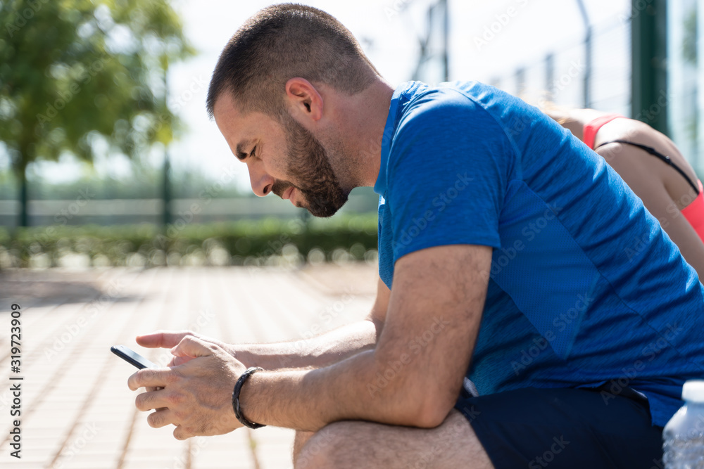 Profile of a man in a tennis court using the mobile Profile of a man in a tennis court using the mobile