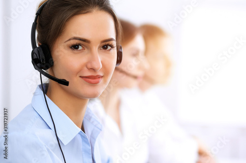 Call center. Focus on beautiful business woman using headset in sunny office